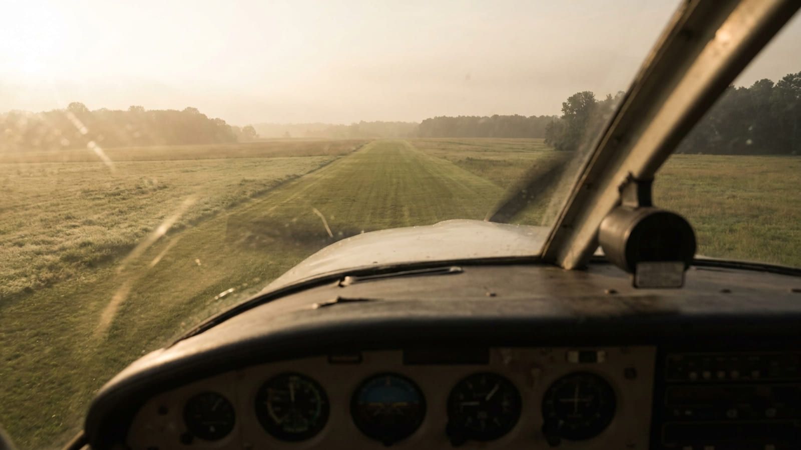 Blick über das Instrumentenbrett eines Kleinflugzeugs im Endanflug auf eine Graspiste